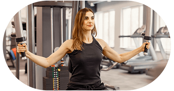 Mulher branca sentada em aparelho de musculação na academia.